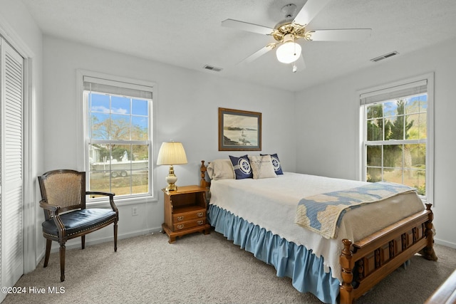 carpeted bedroom with multiple windows, ceiling fan, and a closet