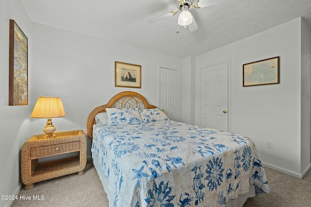 bedroom with ceiling fan, light colored carpet, and a textured ceiling