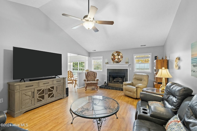 living room featuring a tile fireplace, ceiling fan, light hardwood / wood-style flooring, and high vaulted ceiling