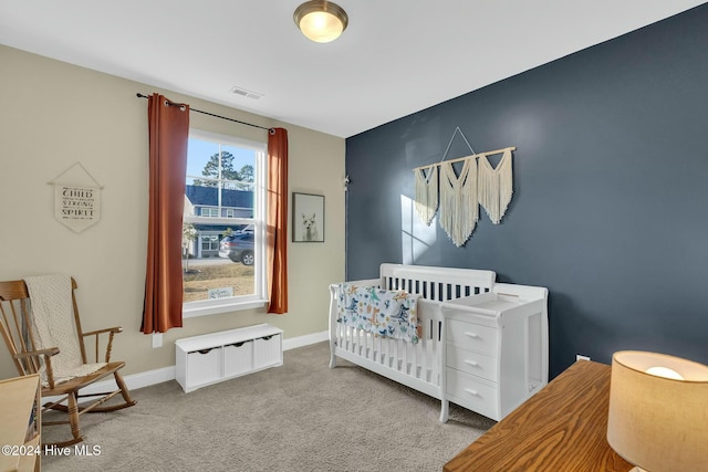 bedroom with light carpet and a nursery area