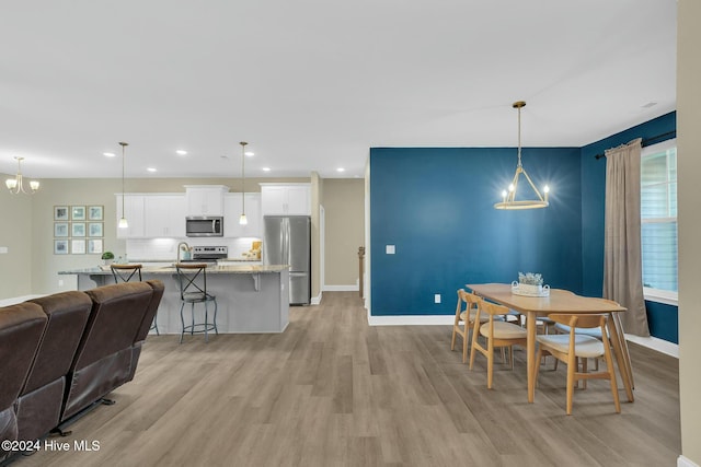 dining room featuring an inviting chandelier, sink, and light hardwood / wood-style flooring