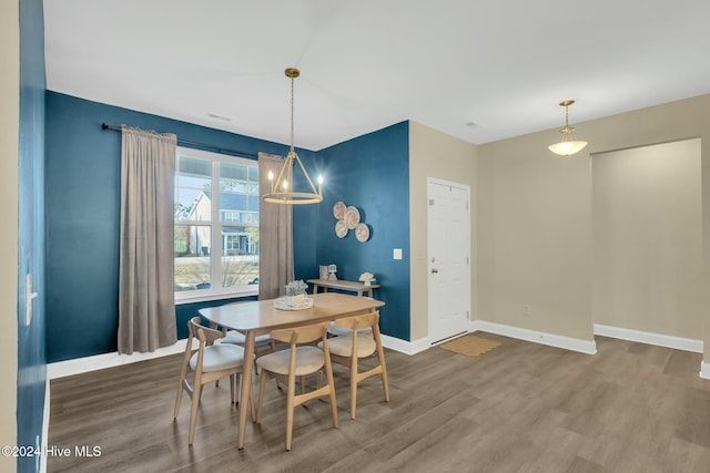 dining room featuring wood-type flooring and an inviting chandelier