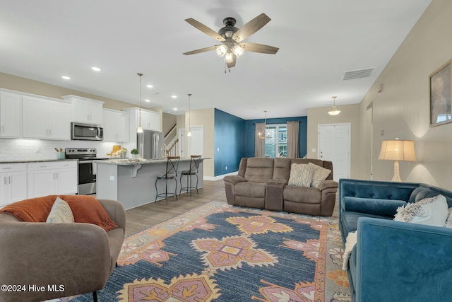 living room with ceiling fan and light hardwood / wood-style flooring