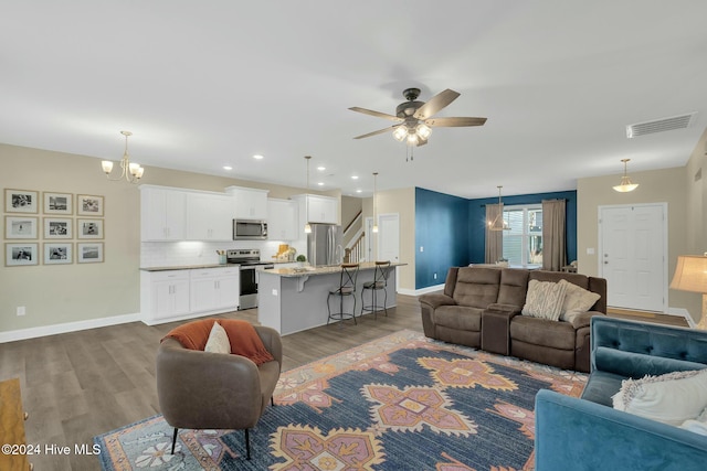 living room with hardwood / wood-style floors and ceiling fan with notable chandelier