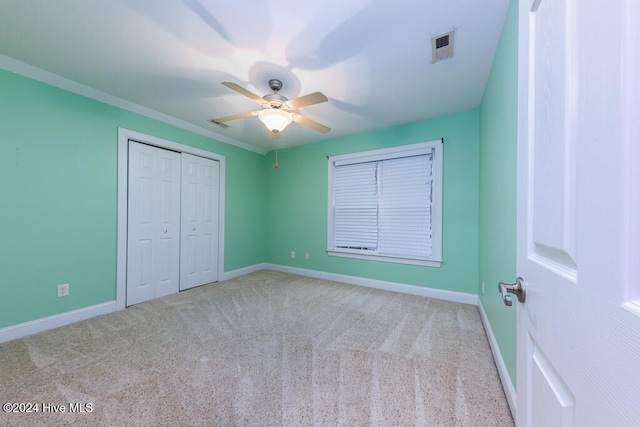 unfurnished bedroom with ceiling fan, crown molding, light carpet, and a closet