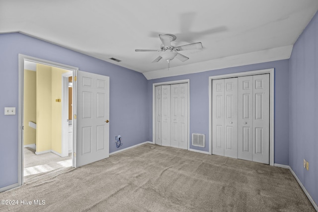 unfurnished bedroom with multiple closets, ceiling fan, and light colored carpet