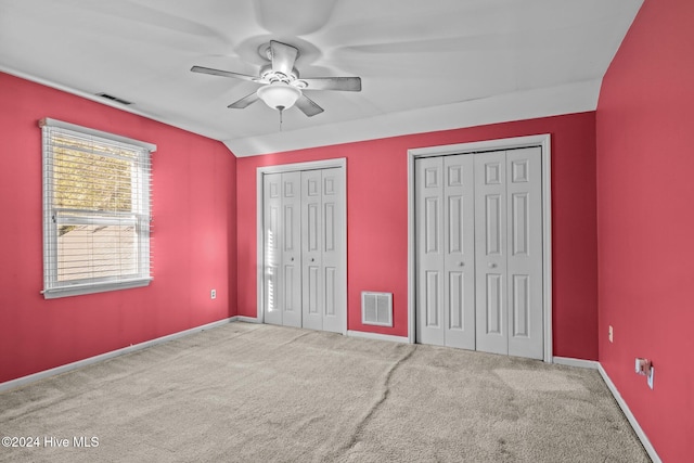 unfurnished bedroom featuring ceiling fan, carpet floors, and two closets