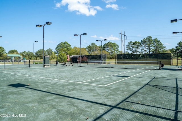 view of tennis court with community basketball court and fence