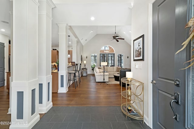 foyer entrance with decorative columns, ceiling fan, dark wood-type flooring, and lofted ceiling