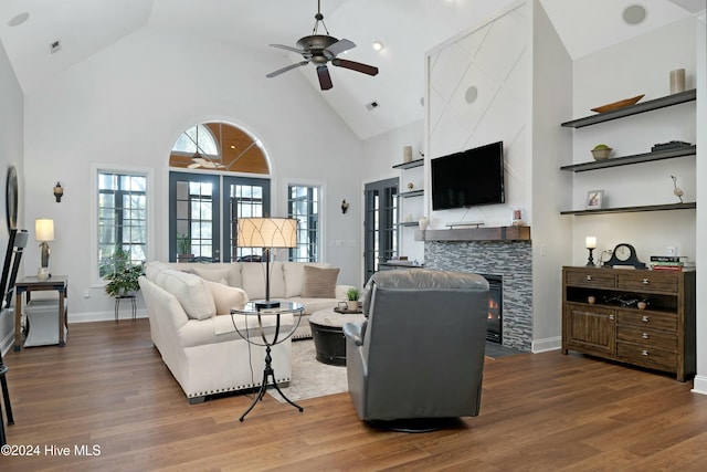 living room featuring ceiling fan, a fireplace, high vaulted ceiling, and wood-type flooring