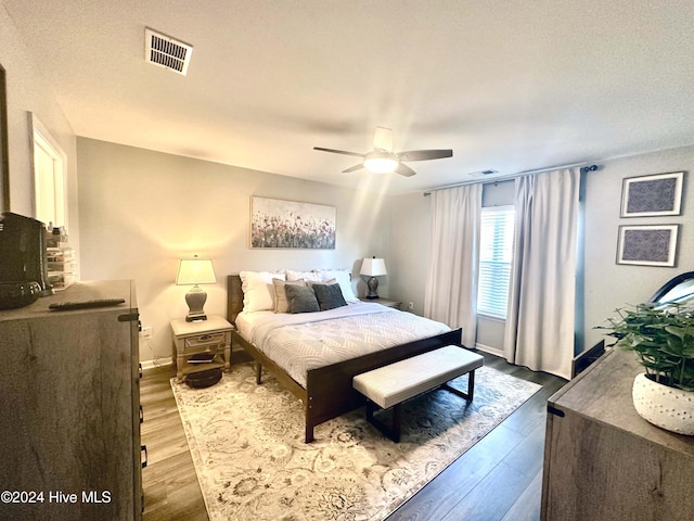 bedroom with ceiling fan, hardwood / wood-style floors, and a textured ceiling