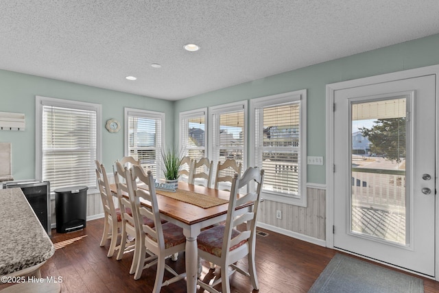 dining room featuring a textured ceiling, dark wood-type flooring, and a wealth of natural light