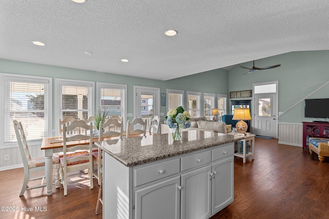 kitchen featuring a textured ceiling, a center island, lofted ceiling, ceiling fan, and dark hardwood / wood-style flooring