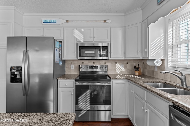 kitchen featuring stainless steel appliances, stone countertops, white cabinetry, and sink