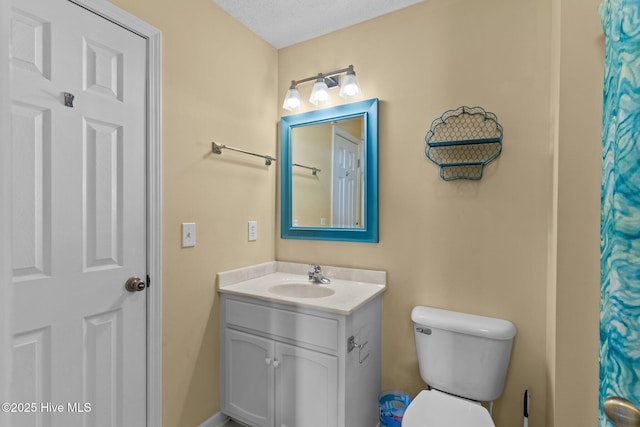 bathroom featuring a textured ceiling, vanity, and toilet