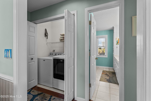 laundry area featuring a textured ceiling, washing machine and dryer, and light tile patterned floors