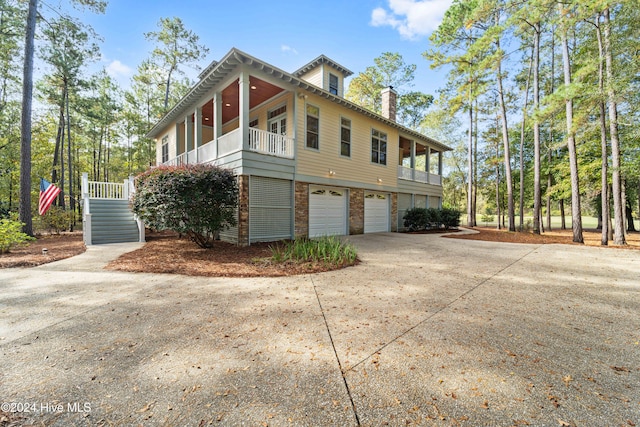 view of side of property featuring an attached garage, a chimney, concrete driveway, and brick siding