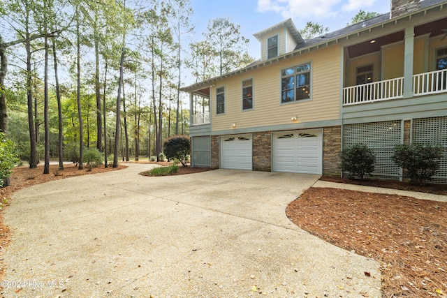 view of side of home featuring driveway, stone siding, and an attached garage