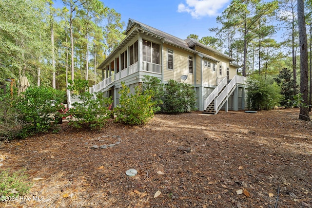 view of side of home featuring a sunroom and stairs