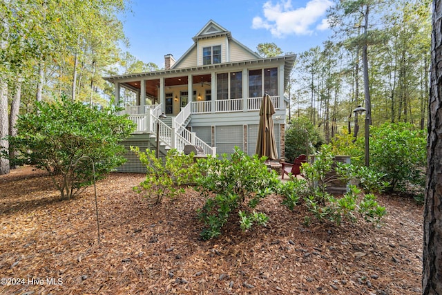 view of front of property featuring a sunroom, stairs, a chimney, and a patio