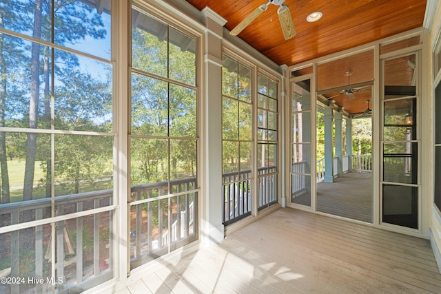 unfurnished sunroom with wood ceiling and a ceiling fan