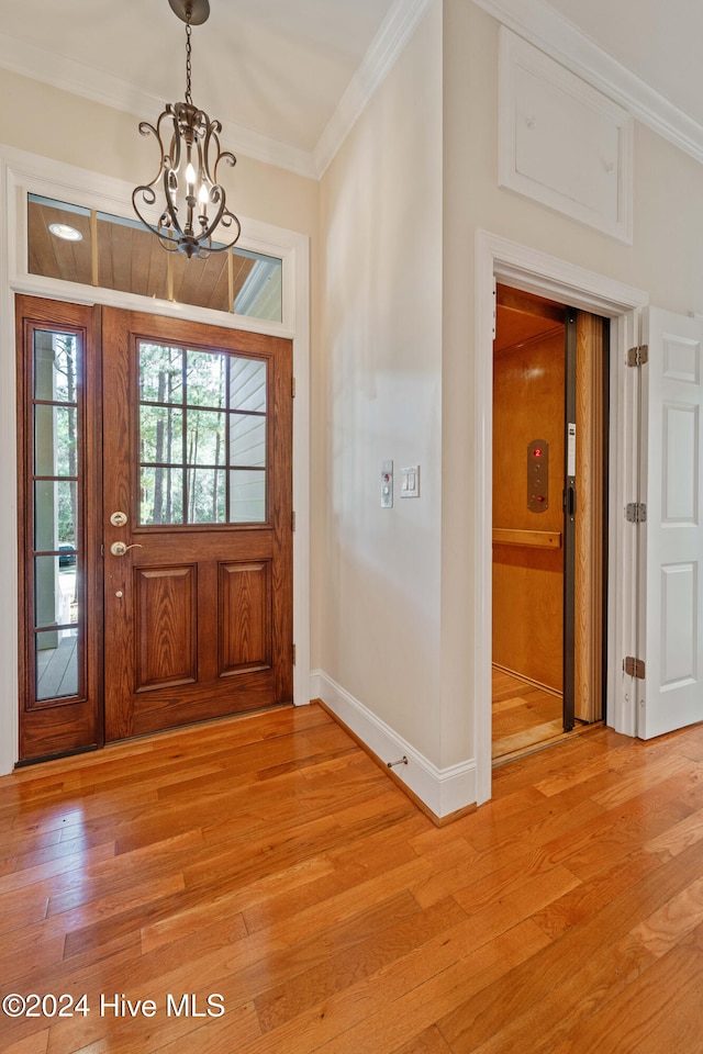 entryway featuring a chandelier, ornamental molding, light wood-style flooring, and baseboards