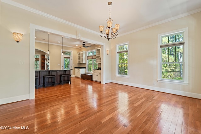 unfurnished living room with crown molding, hardwood / wood-style floors, and baseboards