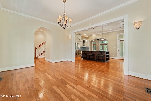 interior space with ornamental molding, a notable chandelier, light wood-style flooring, and baseboards