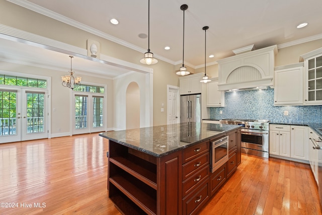 kitchen with premium appliances, light wood-type flooring, and backsplash