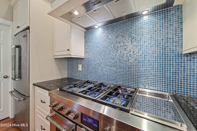 kitchen with stainless steel appliances, backsplash, white cabinets, and range hood