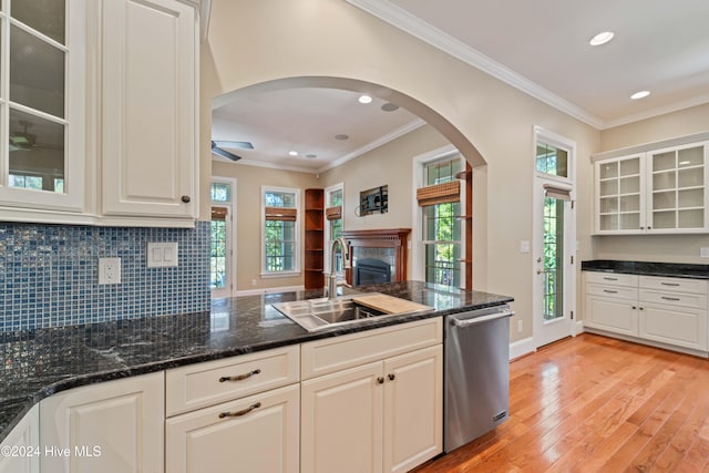 kitchen with ornamental molding, a sink, light wood finished floors, and stainless steel dishwasher