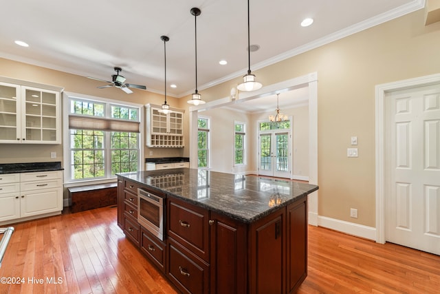 kitchen with glass insert cabinets, baseboards, ornamental molding, and light wood finished floors