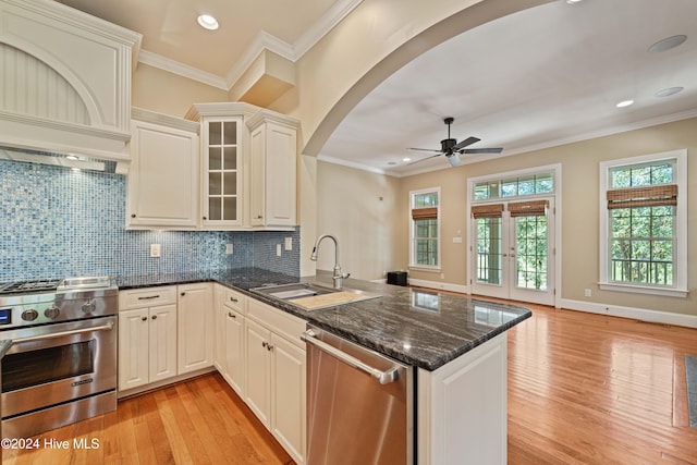 kitchen with stainless steel appliances, crown molding, a sink, and a peninsula