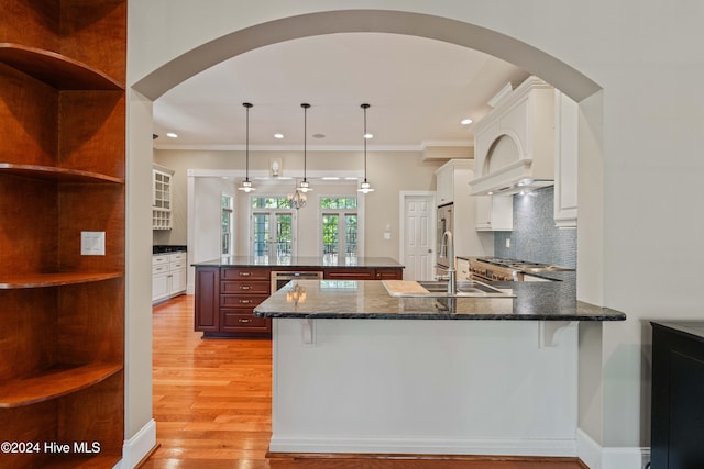 kitchen with tasteful backsplash, light wood-type flooring, white cabinetry, and crown molding