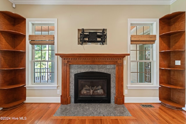 unfurnished living room with ornamental molding, a high end fireplace, baseboards, and wood finished floors