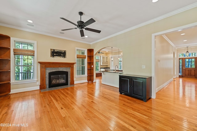 unfurnished living room featuring light wood finished floors, a fireplace, baseboards, and crown molding