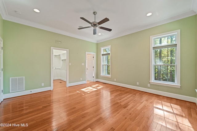 unfurnished bedroom with light wood-style flooring, multiple windows, visible vents, and crown molding