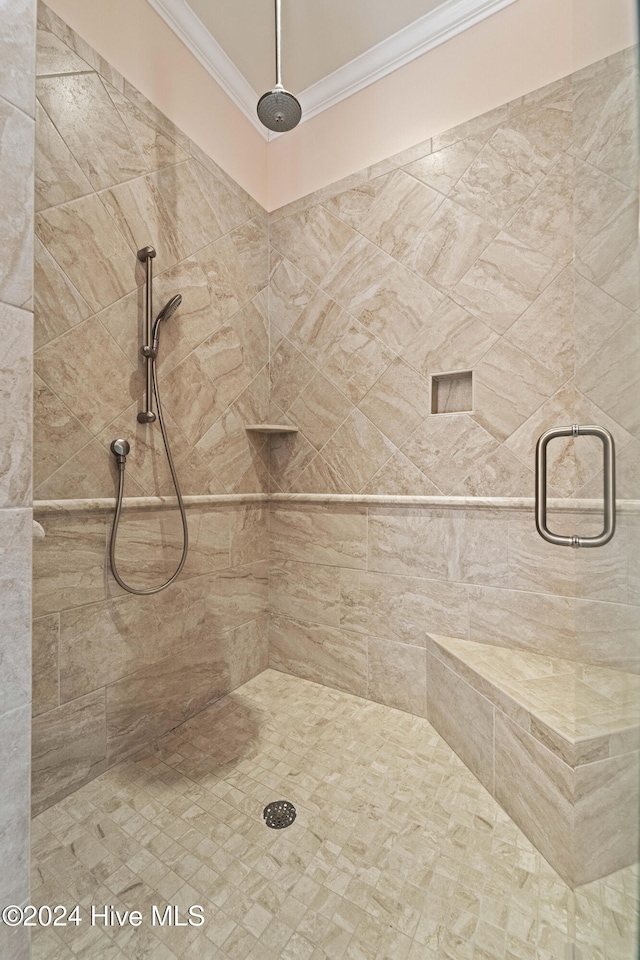 bathroom featuring crown molding and a tile shower