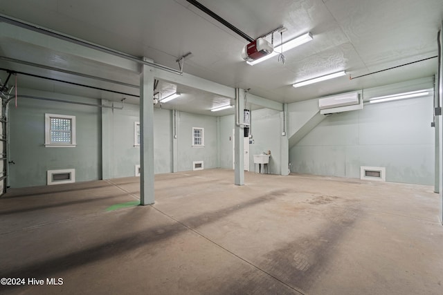 garage featuring a wall mounted AC, a sink, and a garage door opener