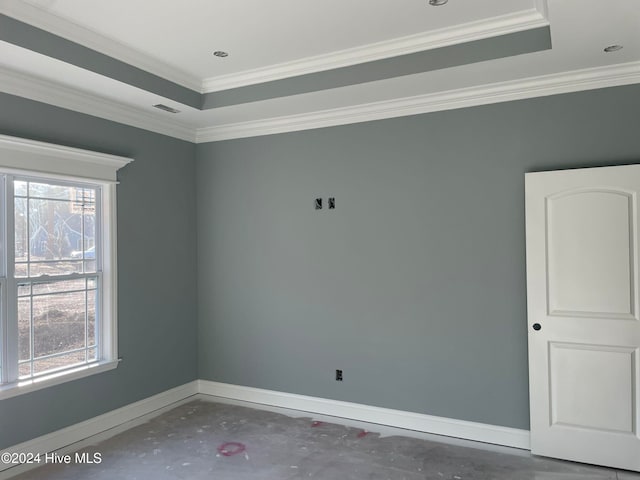 spare room featuring ornamental molding, plenty of natural light, concrete floors, and a tray ceiling