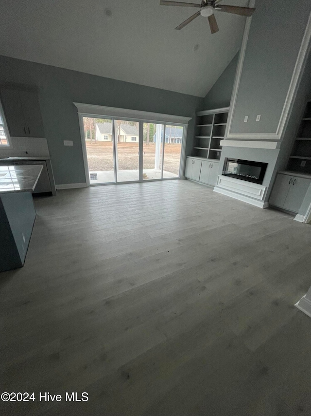 unfurnished living room with hardwood / wood-style floors, built in shelves, high vaulted ceiling, and ceiling fan