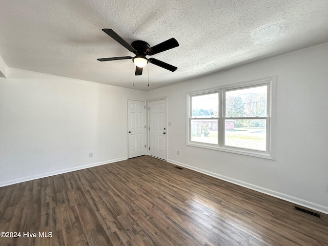 empty room featuring a textured ceiling, dark hardwood / wood-style floors, and ceiling fan