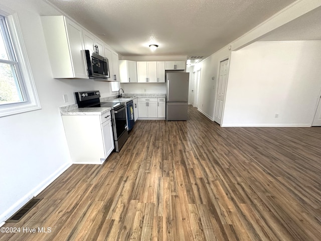 kitchen with sink, a textured ceiling, dark hardwood / wood-style flooring, white cabinetry, and stainless steel appliances