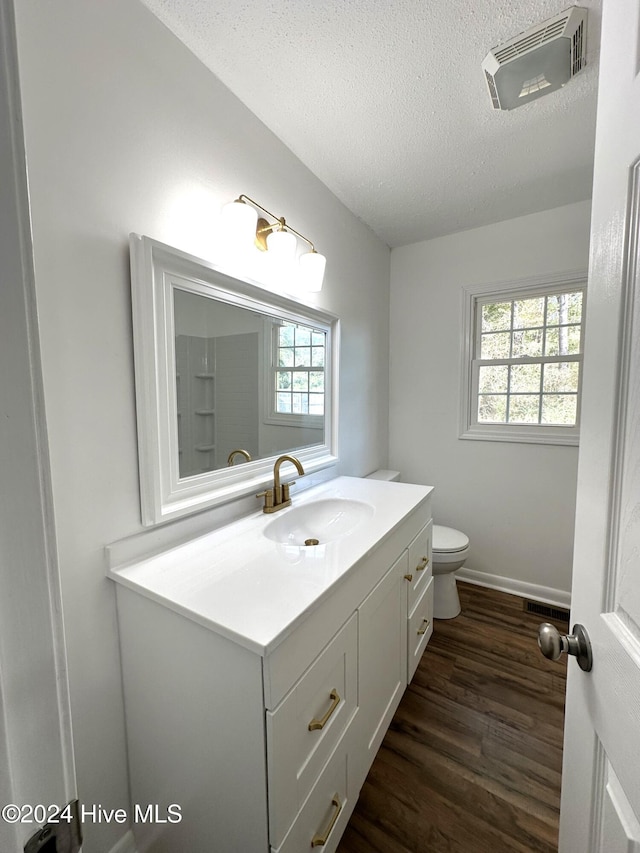 bathroom with hardwood / wood-style floors, vanity, a healthy amount of sunlight, and toilet