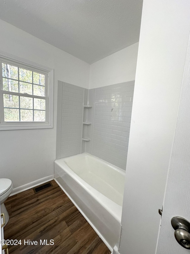 bathroom featuring tiled shower / bath combo, toilet, and wood-type flooring