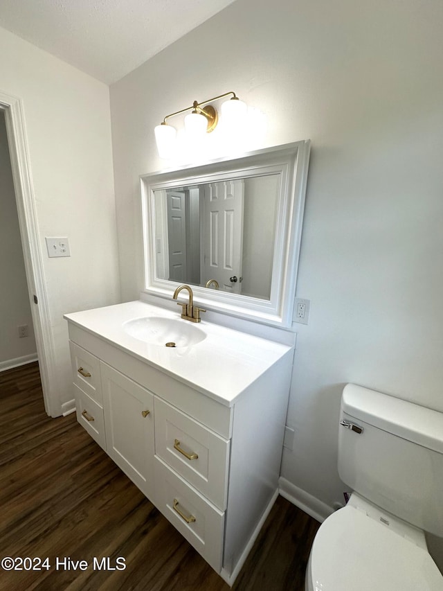 bathroom with hardwood / wood-style floors, vanity, and toilet