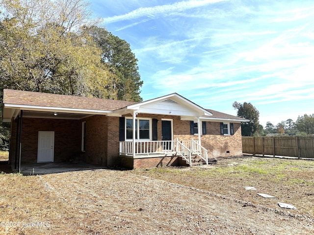 ranch-style house with a porch and a carport