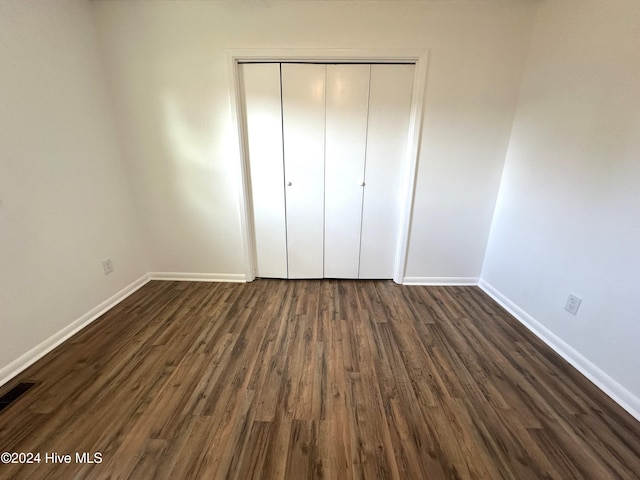 unfurnished bedroom with a closet and dark hardwood / wood-style flooring