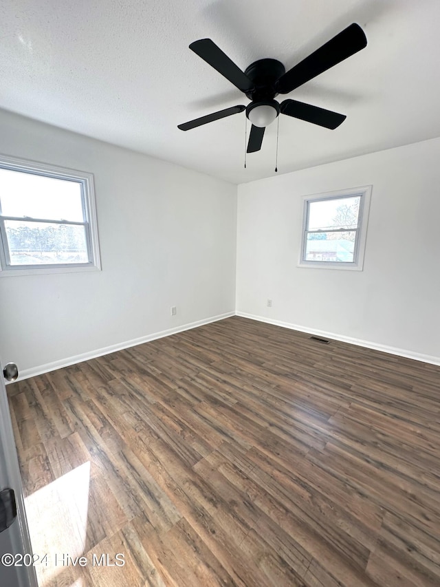 unfurnished room featuring a healthy amount of sunlight, dark hardwood / wood-style flooring, and a textured ceiling