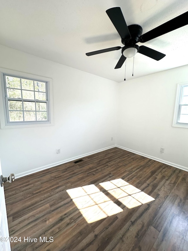 empty room with a wealth of natural light, ceiling fan, and dark hardwood / wood-style floors